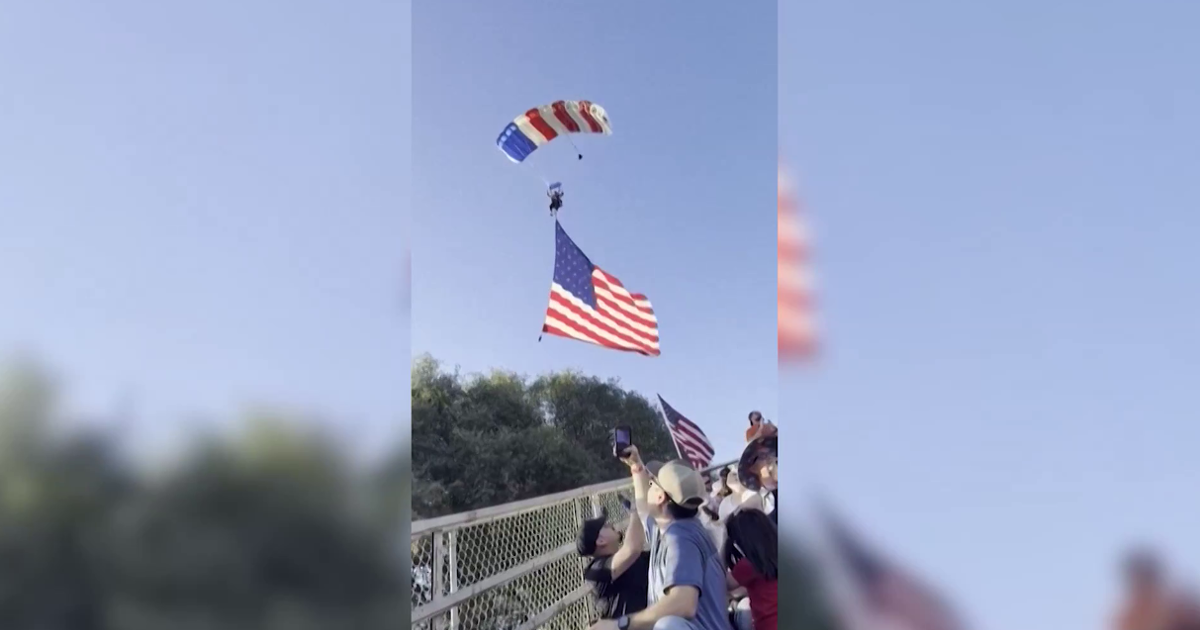 Kaliforniya’da rodeo etkinliği sırasında iniş yapan paraşütçünün alandaki masaların üzerine düştüğü an