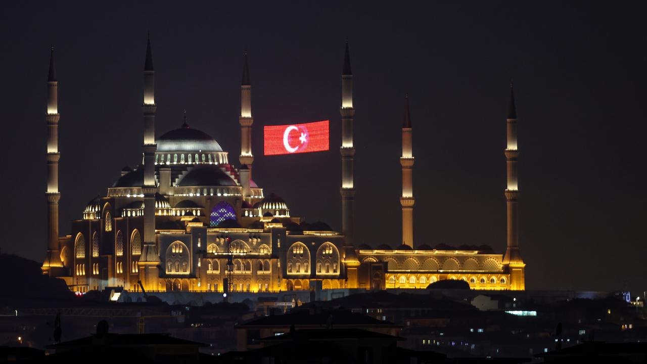 Gece saatlerinde ışıkları açık bir cami ve aydınlatılmış minareleri